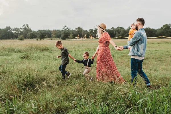 A family walking hand in hand through a tall grass meadow