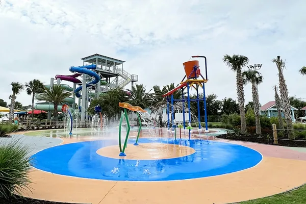 An empty splash pad with water play towers and palm trees on a sunny day